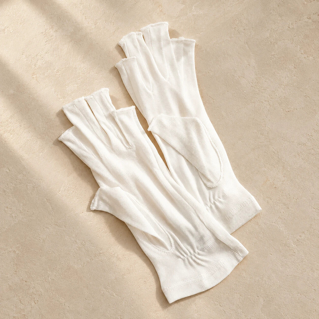 Ivory silk fingerless gloves on a warm neutral surface